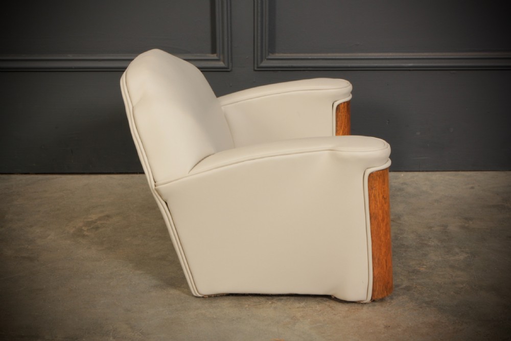 A miniature Art Deco three-piece suite featuring a small sofa and two matching armchairs upholstered in cream leather with polished curved wood arm fronts. View IX
