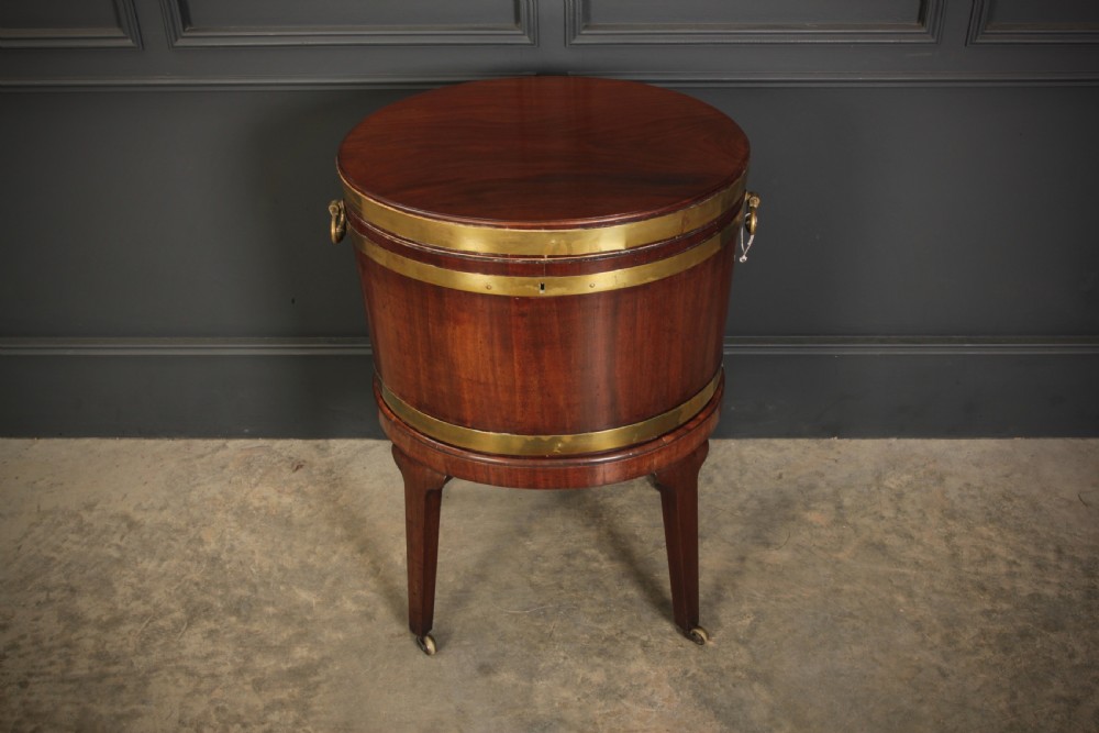 An oval Georgian mahogany wine cooler with brass binding straps, side handles, and tapered square legs on brass castors. View III