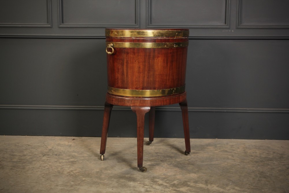 An oval Georgian mahogany wine cooler with brass binding straps, side handles, and tapered square legs on brass castors. View XII
