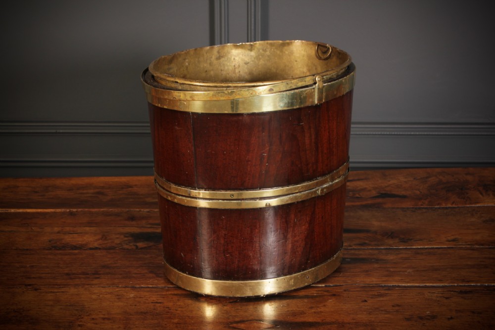 A Georgian staved mahogany peat bucket bound with polished brass hoops and fitted with a brass liner.