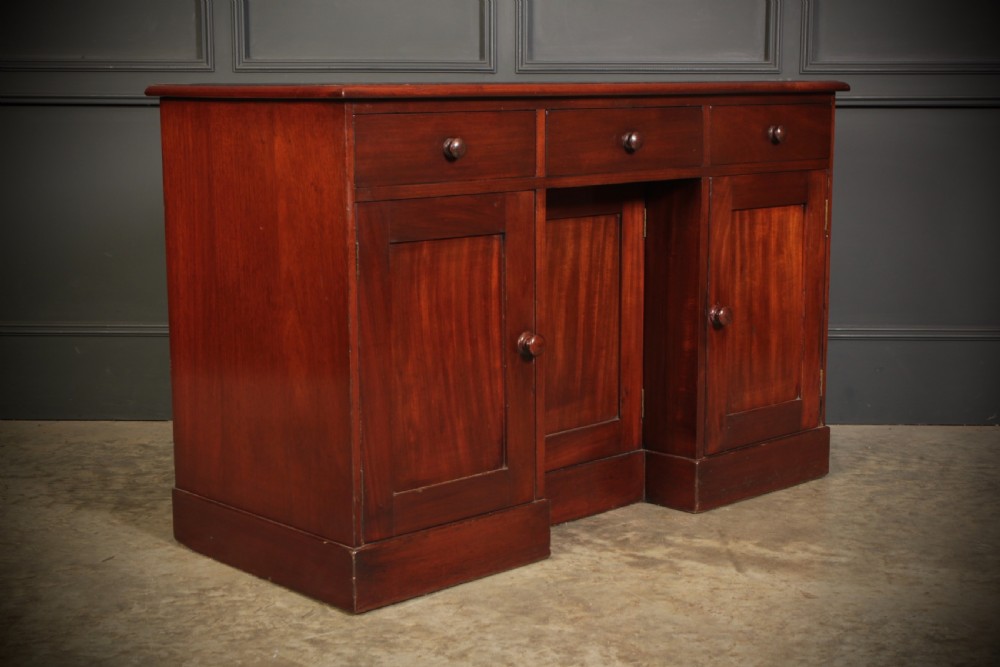 An Early Victorian mahogany kneehole desk with a dark leather writing surface, three frieze drawers, side cupboards, and turned wooden handles. View II