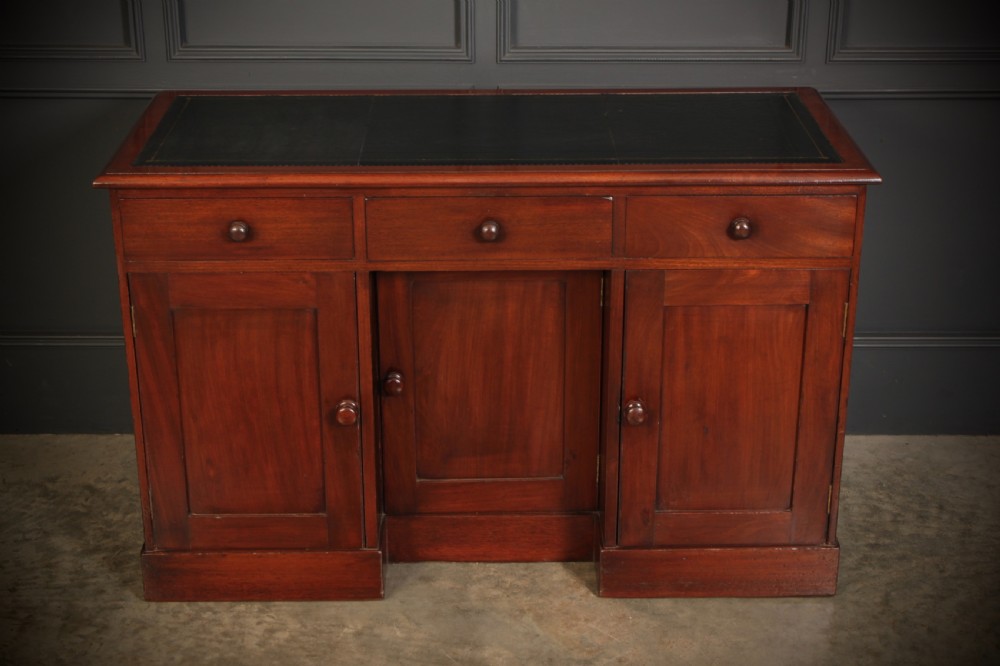 An Early Victorian mahogany kneehole desk with a dark leather writing surface, three frieze drawers, side cupboards, and turned wooden handles. View III