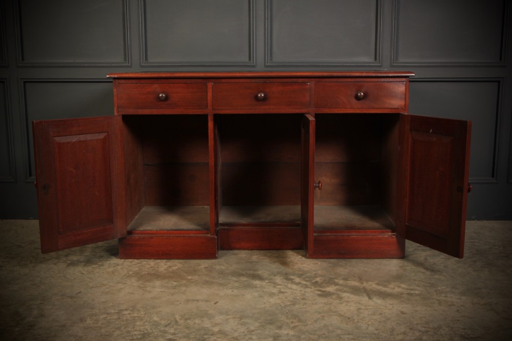 An Early Victorian mahogany kneehole desk with a dark leather writing surface, three frieze drawers, side cupboards, and turned wooden handles. View VI