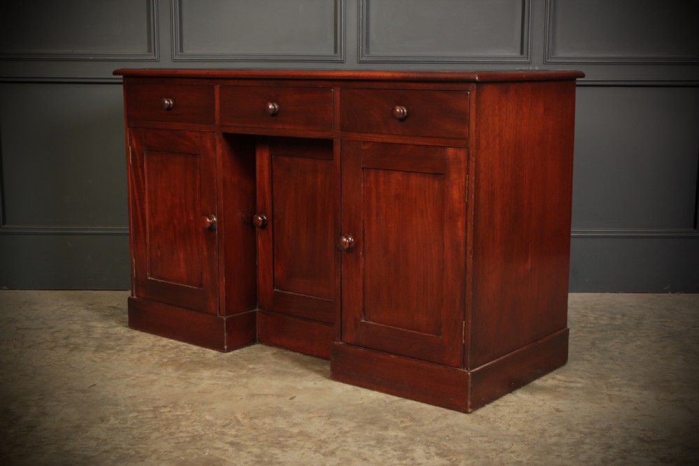 An Early Victorian mahogany kneehole desk with a dark leather writing surface, three frieze drawers, side cupboards, and turned wooden handles. View VIII