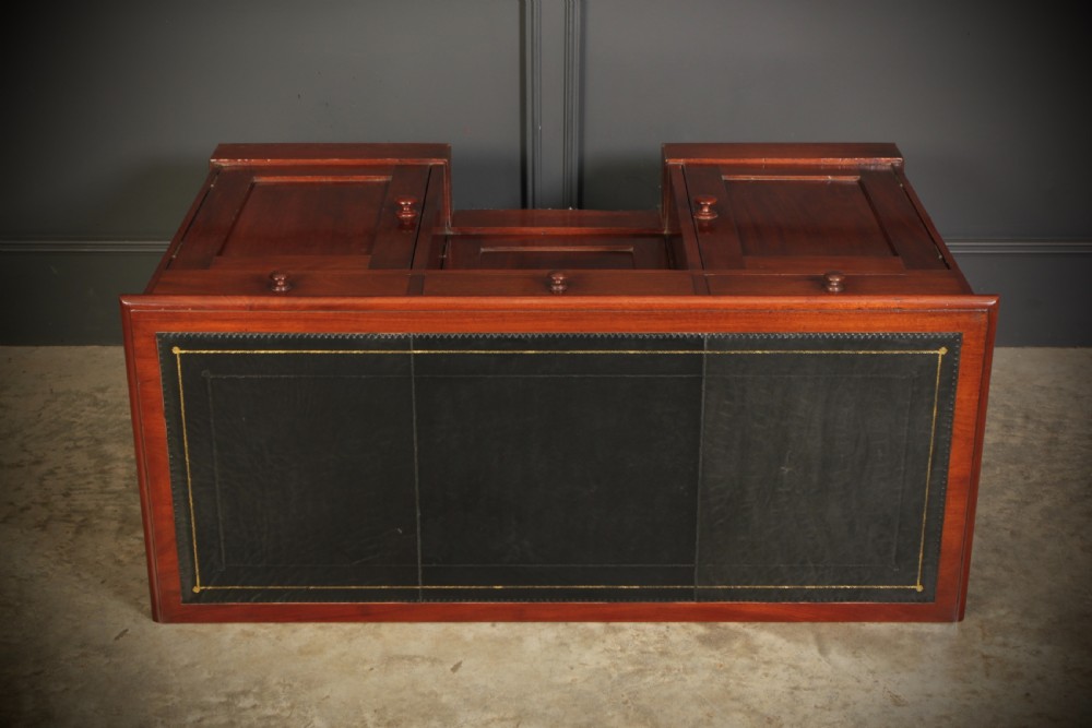 An Early Victorian mahogany kneehole desk with a dark leather writing surface, three frieze drawers, side cupboards, and turned wooden handles. View XII