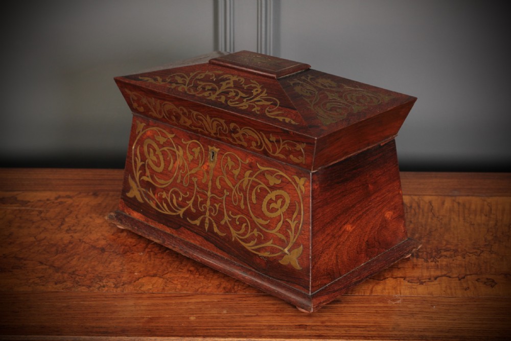 A Regency sarcophagus-form rosewood tea caddy featuring ornate foliate brass inlay across the lid and front panel. View III