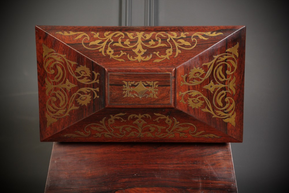 A Regency sarcophagus-form rosewood tea caddy featuring ornate foliate brass inlay across the lid and front panel. View VIII