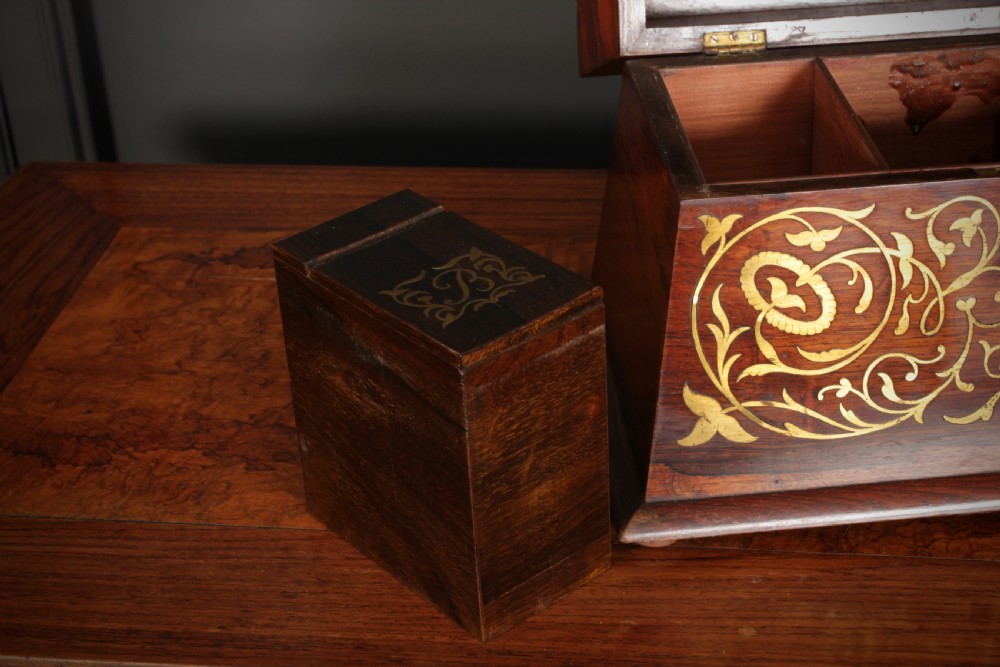 A Regency sarcophagus-form rosewood tea caddy featuring ornate foliate brass inlay across the lid and front panel. View IX