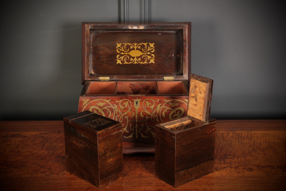 A Regency sarcophagus-form rosewood tea caddy featuring ornate foliate brass inlay across the lid and front panel. View XI