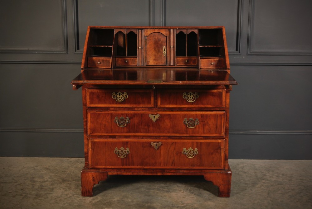 An eighteenth-century Queen Anne walnut slant-front bureau featuring brass drop handles, multiple drawers, and bracket feet. View V