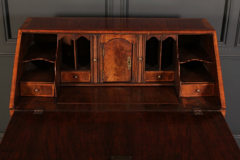 An eighteenth-century Queen Anne walnut slant-front bureau featuring brass drop handles, multiple drawers, and bracket feet. View VI