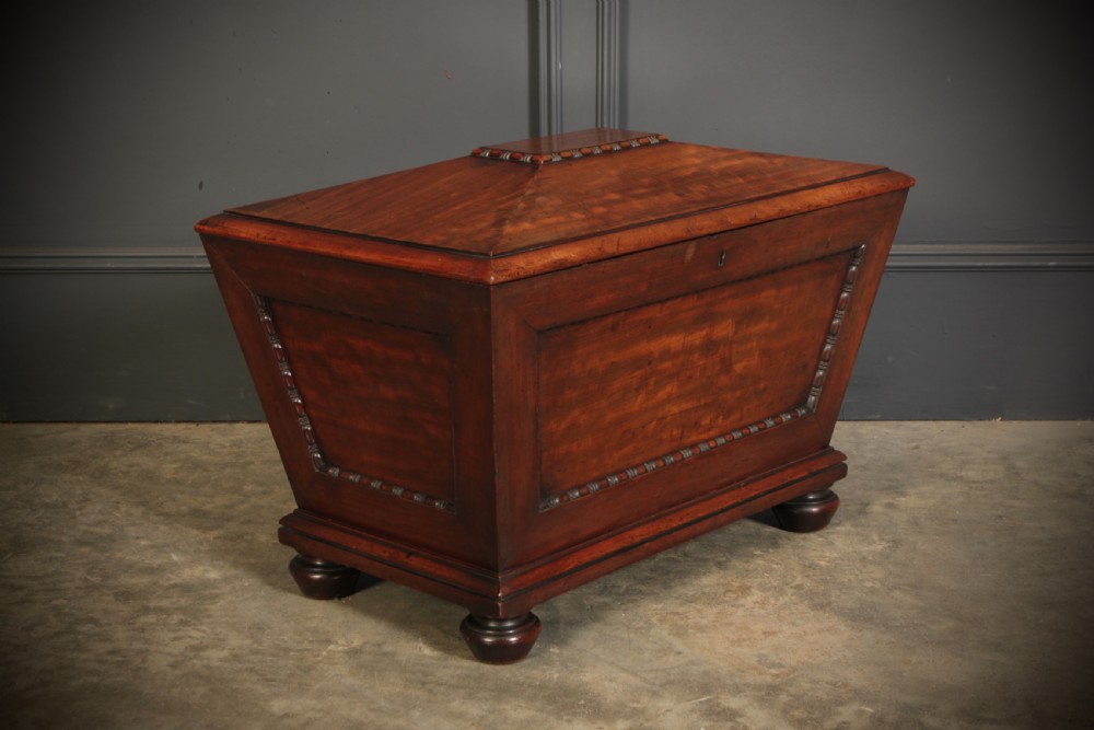 A Regency period mahogany sarcophagus cellarette featuring tapered sides, beaded moulding, and compressed turned feet. View III