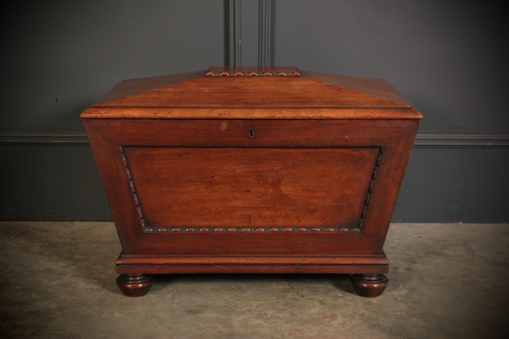 A Regency period mahogany sarcophagus cellarette featuring tapered sides, beaded moulding, and compressed turned feet. View VI