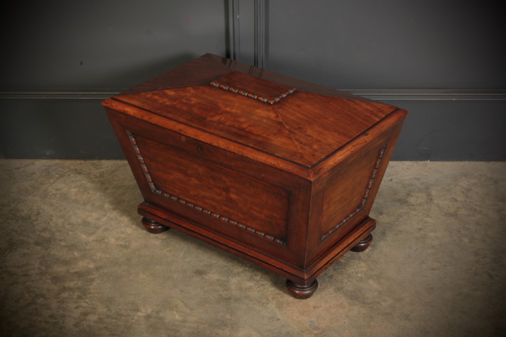 A Regency period mahogany sarcophagus cellarette featuring tapered sides, beaded moulding, and compressed turned feet. View VII