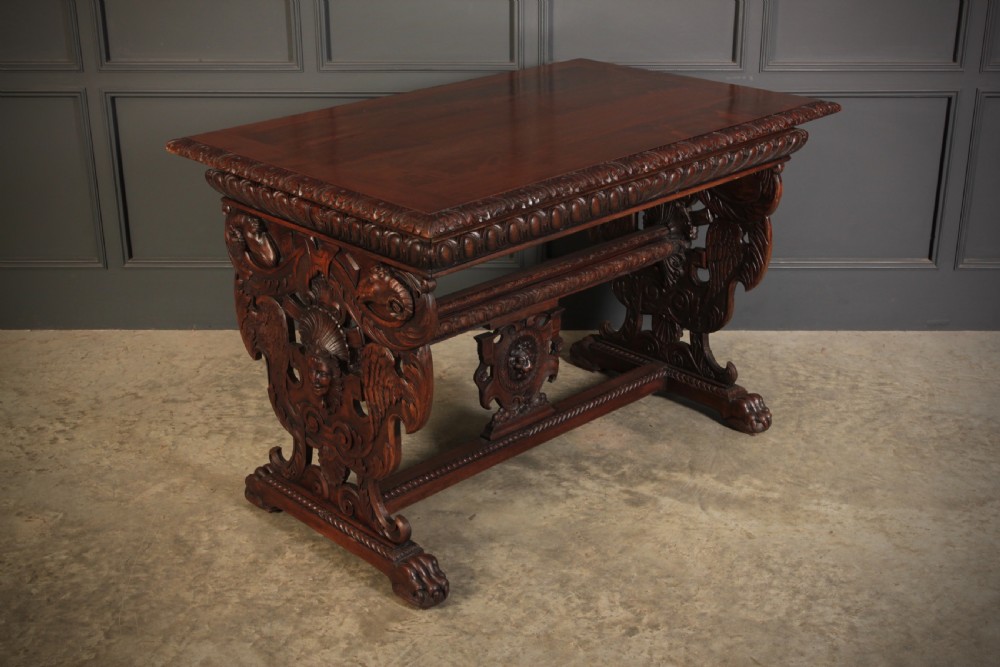A dark walnut centre table featuring ornate carved trestle supports, carved human and animal masks, a gadrooned apron, and lion paw feet. View III