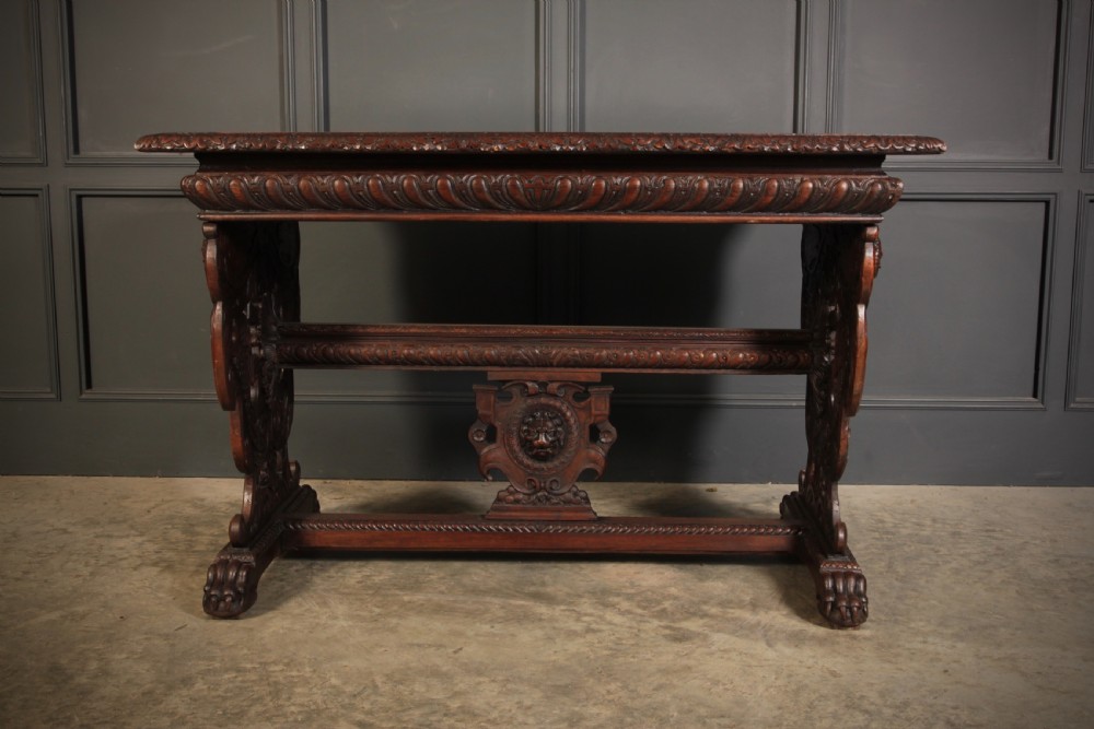 A dark walnut centre table featuring ornate carved trestle supports, carved human and animal masks, a gadrooned apron, and lion paw feet. View VI