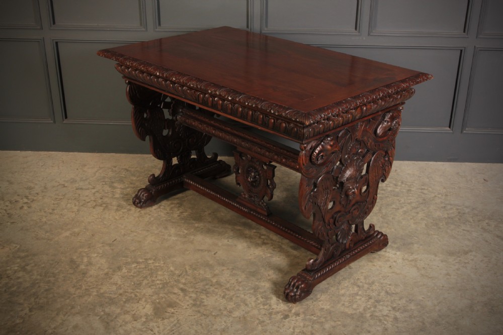 A dark walnut centre table featuring ornate carved trestle supports, carved human and animal masks, a gadrooned apron, and lion paw feet. View IX
