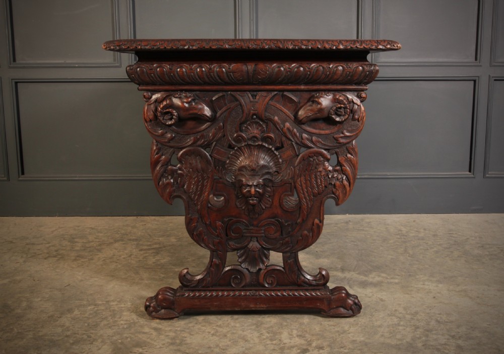 A dark walnut centre table featuring ornate carved trestle supports, carved human and animal masks, a gadrooned apron, and lion paw feet. View XI
