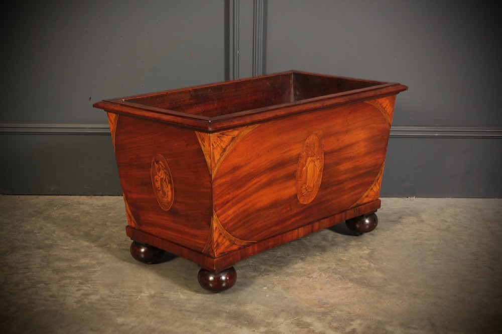 A tapered Georgian mahogany wine cooler with oval marquetry inlays raised on heavy bun feet. View V