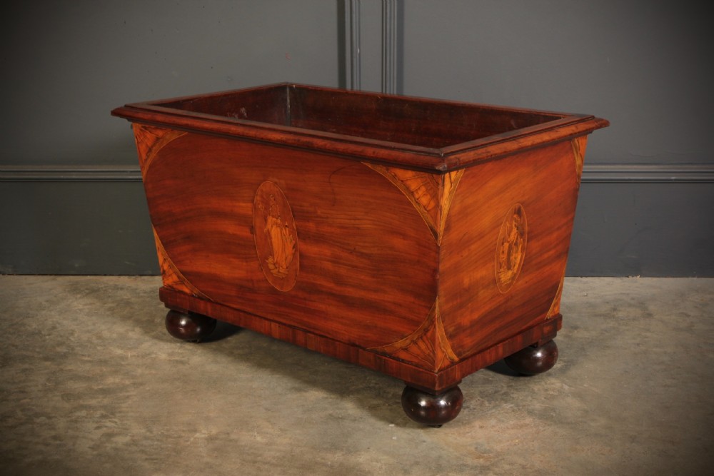 A tapered Georgian mahogany wine cooler with oval marquetry inlays raised on heavy bun feet.