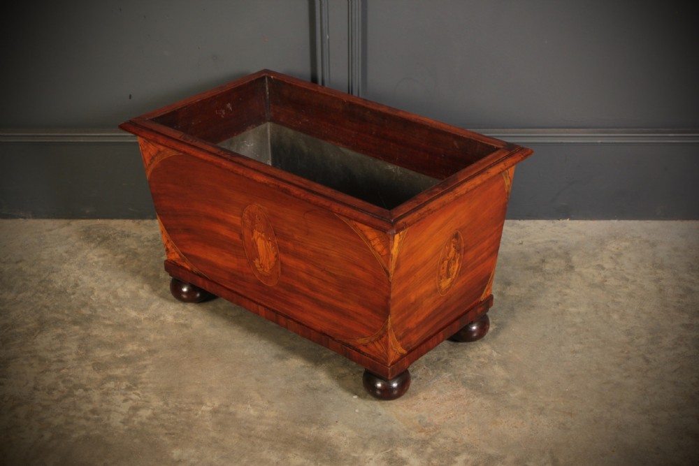 A tapered Georgian mahogany wine cooler with oval marquetry inlays raised on heavy bun feet. View VI