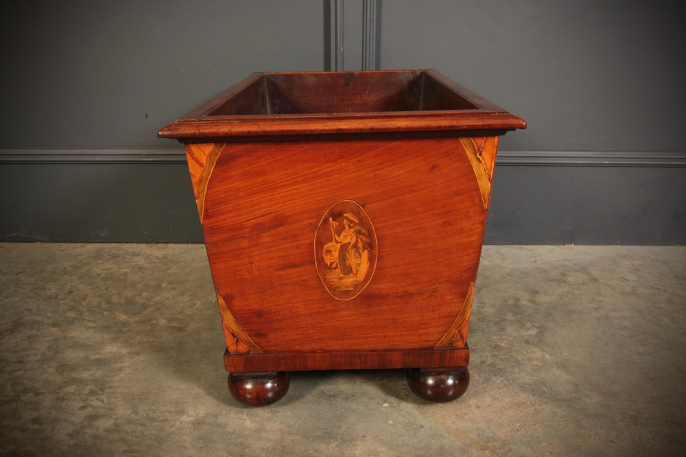 A tapered Georgian mahogany wine cooler with oval marquetry inlays raised on heavy bun feet. View X