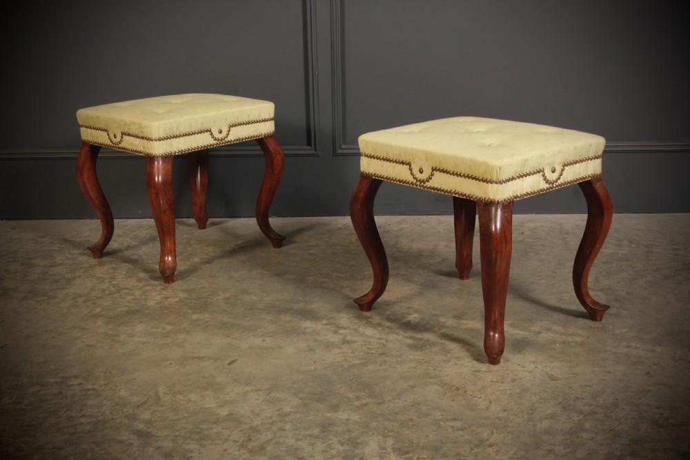 A pair of early Victorian footstools featuring dark mahogany cabriole legs and cream silk buttoned upholstered tops with brass stud detail. View II