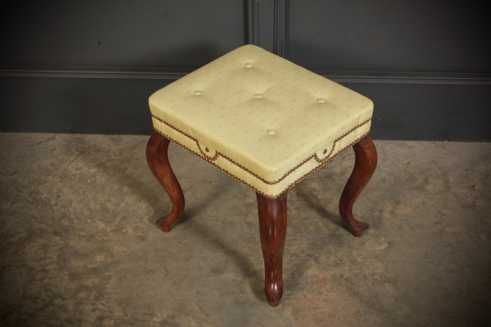 A pair of early Victorian footstools featuring dark mahogany cabriole legs and cream silk buttoned upholstered tops with brass stud detail. View VII