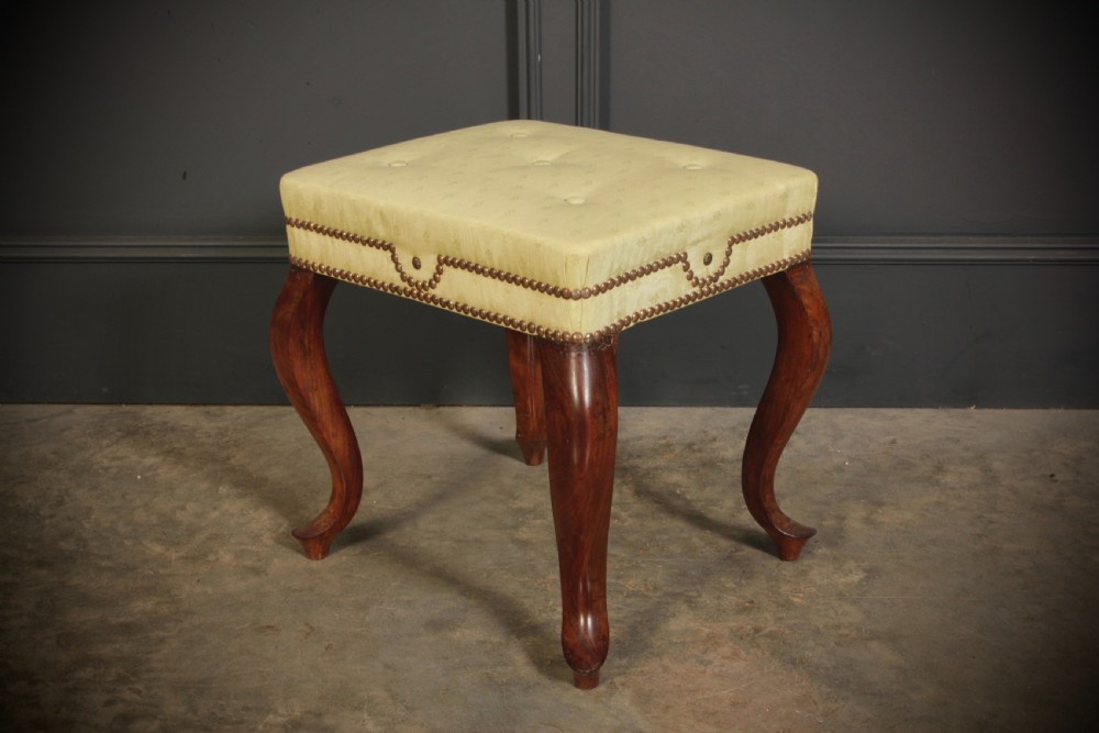 A pair of early Victorian footstools featuring dark mahogany cabriole legs and cream silk buttoned upholstered tops with brass stud detail. View VIII
