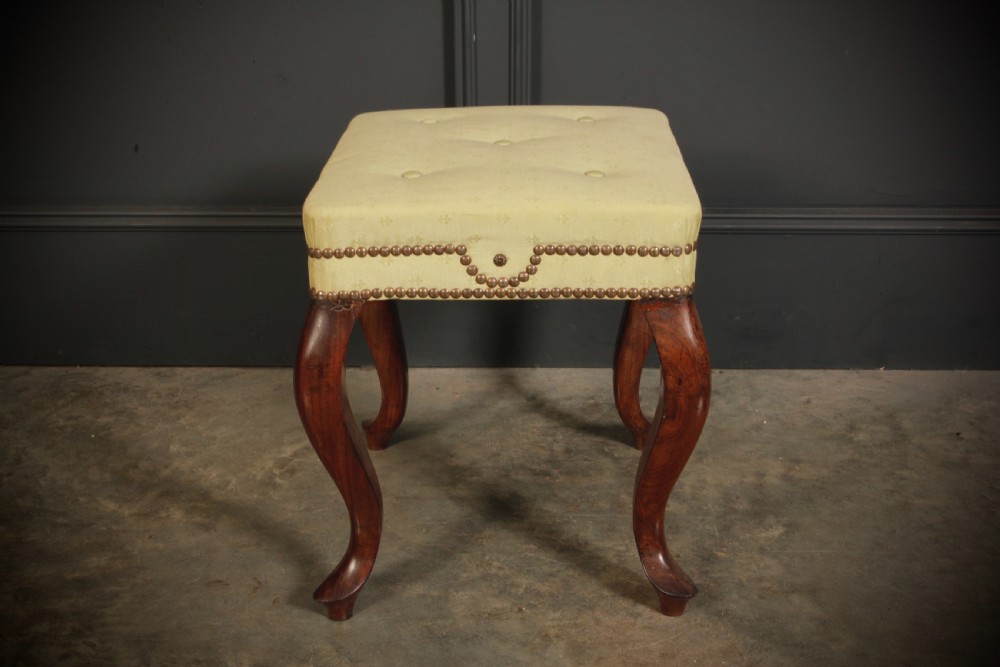 A pair of early Victorian footstools featuring dark mahogany cabriole legs and cream silk buttoned upholstered tops with brass stud detail. View IX