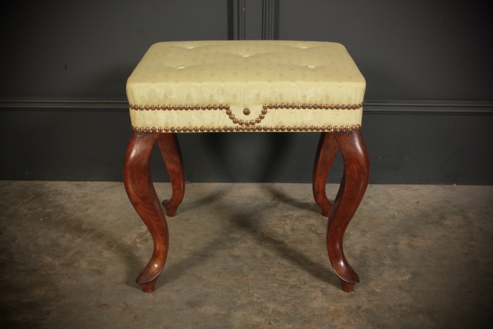 A pair of early Victorian footstools featuring dark mahogany cabriole legs and cream silk buttoned upholstered tops with brass stud detail. View XII