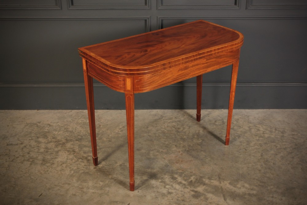 A Regency period mahogany fold-over tea table featuring boxwood line inlay, rounded front corners, and four square tapered legs.