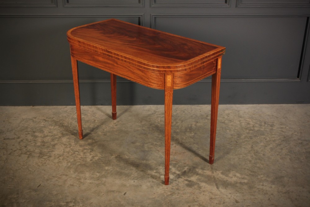 A Regency period mahogany fold-over tea table featuring boxwood line inlay, rounded front corners, and four square tapered legs. View V