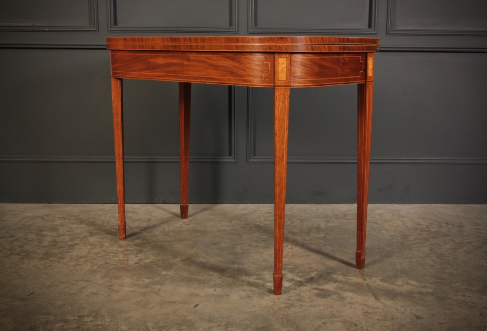 A Regency period mahogany fold-over tea table featuring boxwood line inlay, rounded front corners, and four square tapered legs. View VI