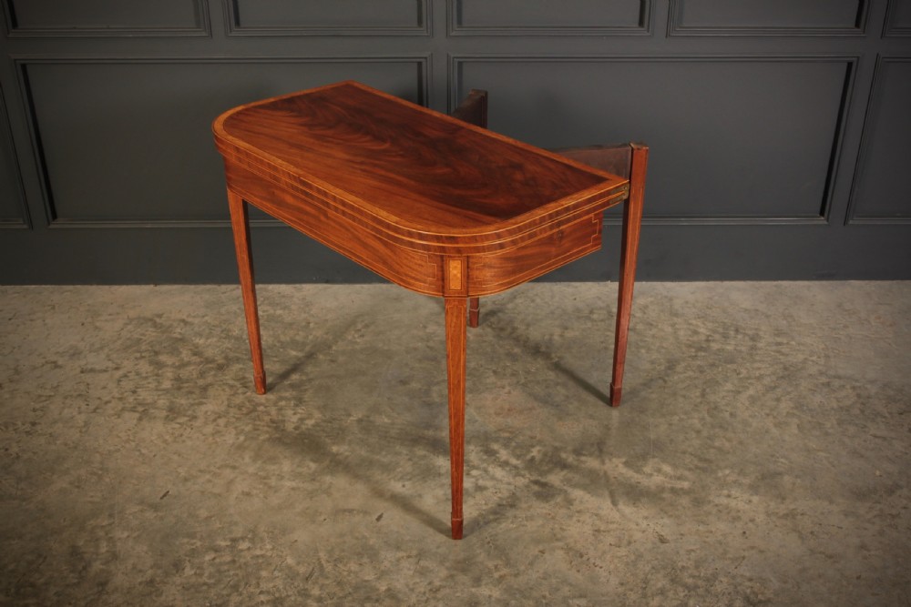 A Regency period mahogany fold-over tea table featuring boxwood line inlay, rounded front corners, and four square tapered legs. View VII
