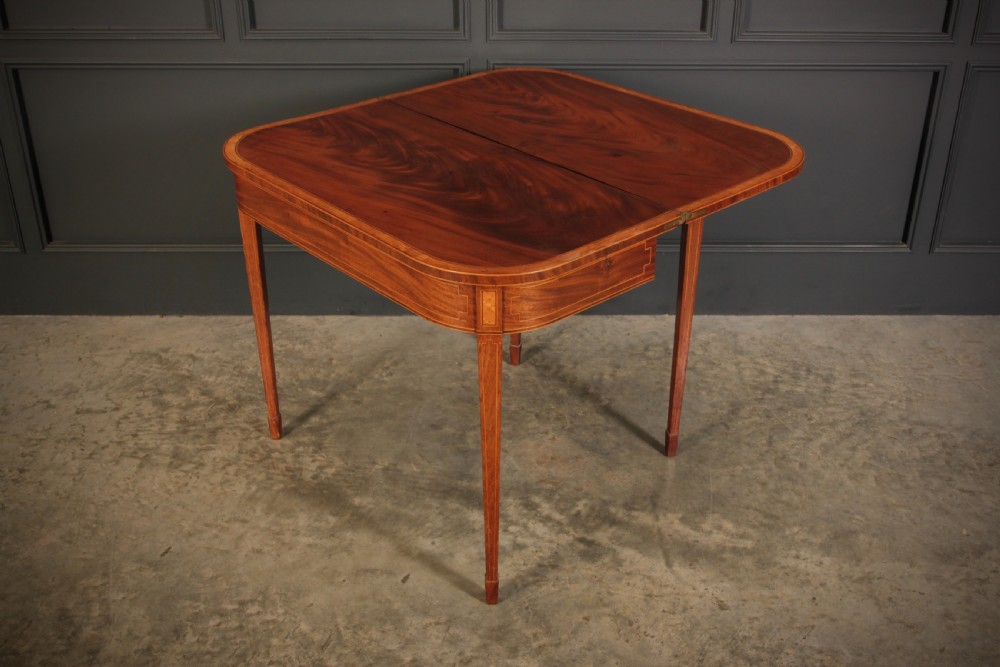 A Regency period mahogany fold-over tea table featuring boxwood line inlay, rounded front corners, and four square tapered legs. View IX