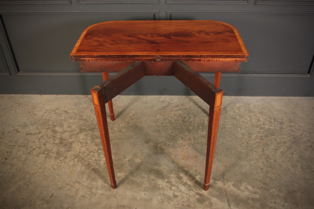 A Regency period mahogany fold-over tea table featuring boxwood line inlay, rounded front corners, and four square tapered legs. View XI