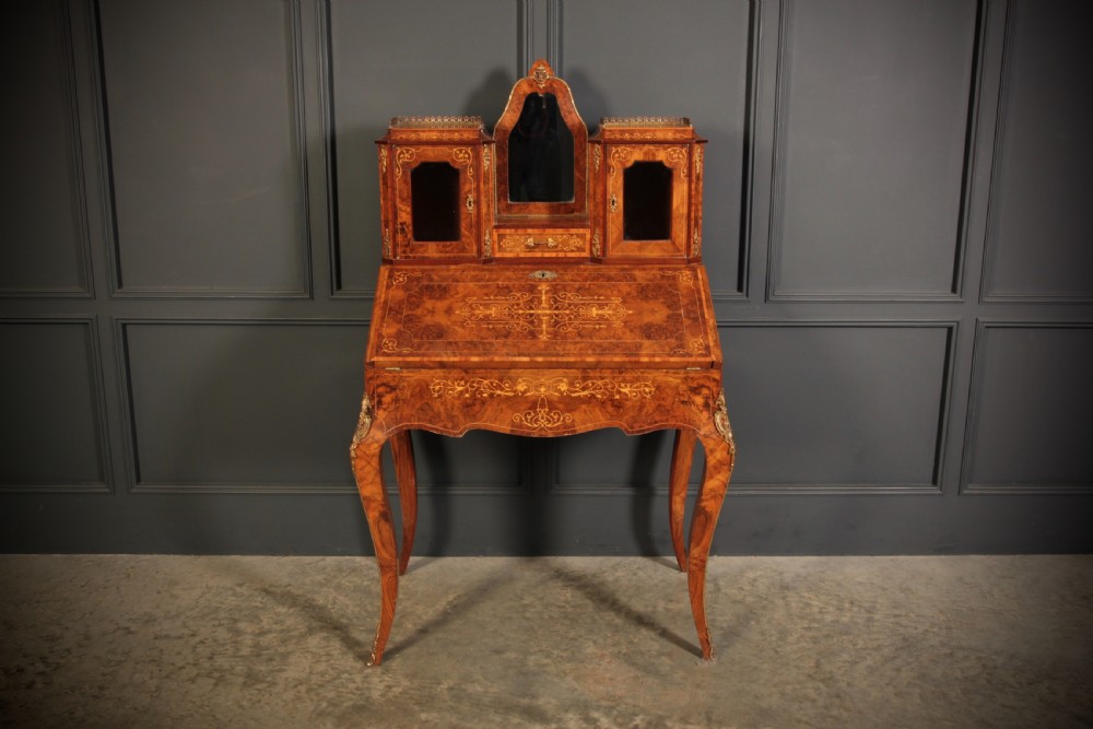 A Victorian burr walnut bonheur du jour writing desk featuring intricate floral marquetry, cabriole legs, brass mounts, and a raised superstructure with small glass cabinets. View II