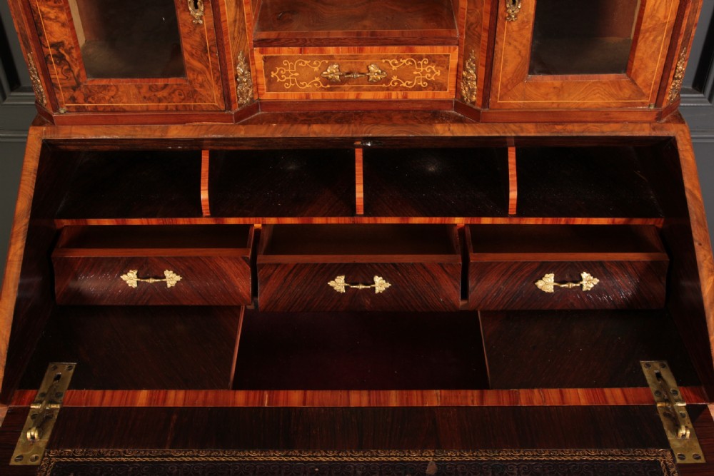 A Victorian burr walnut bonheur du jour writing desk featuring intricate floral marquetry, cabriole legs, brass mounts, and a raised superstructure with small glass cabinets. View V