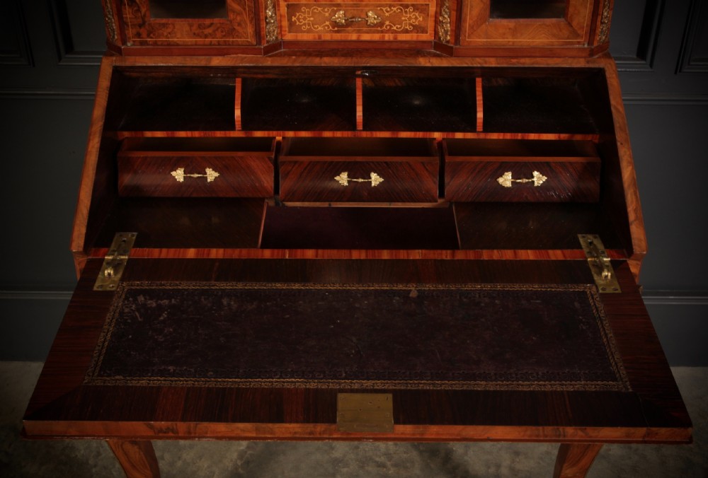 A Victorian burr walnut bonheur du jour writing desk featuring intricate floral marquetry, cabriole legs, brass mounts, and a raised superstructure with small glass cabinets. View VII