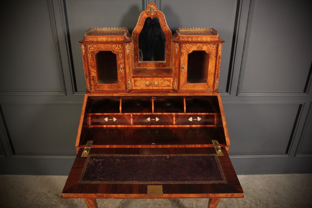 A Victorian burr walnut bonheur du jour writing desk featuring intricate floral marquetry, cabriole legs, brass mounts, and a raised superstructure with small glass cabinets. View VIII