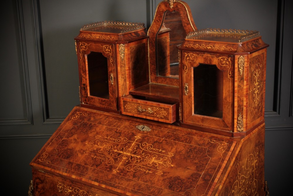 A Victorian burr walnut bonheur du jour writing desk featuring intricate floral marquetry, cabriole legs, brass mounts, and a raised superstructure with small glass cabinets. View XII