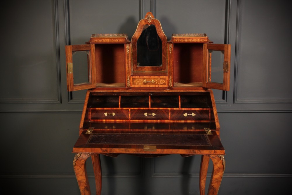 A Victorian burr walnut bonheur du jour writing desk featuring intricate floral marquetry, cabriole legs, brass mounts, and a raised superstructure with small glass cabinets. View XIII