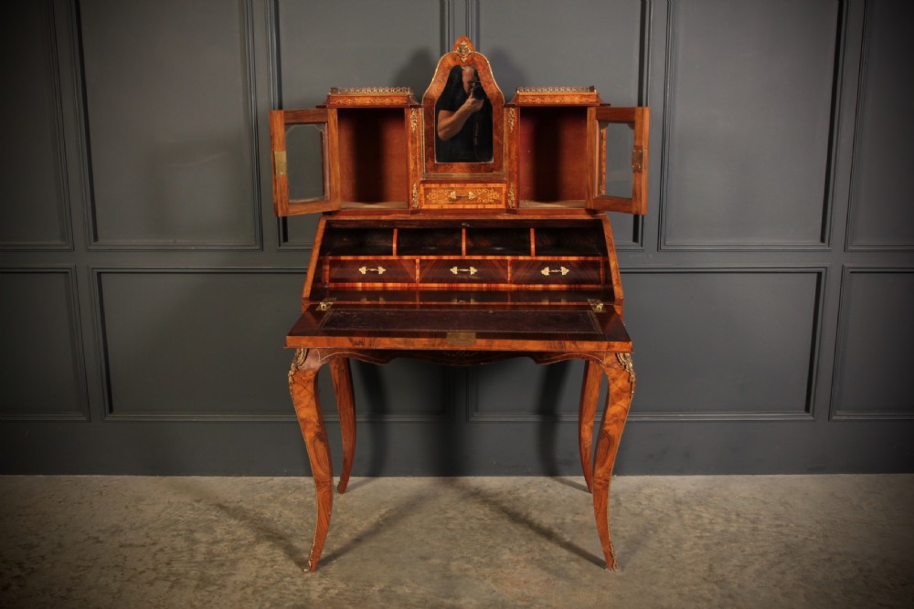 A Victorian burr walnut bonheur du jour writing desk featuring intricate floral marquetry, cabriole legs, brass mounts, and a raised superstructure with small glass cabinets. View XIV
