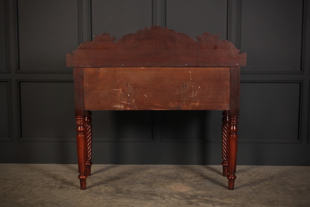 A William IV flame mahogany bow-front sideboard featuring a carved scroll backboard, flame veneer drawer fronts, brass keyhole escutcheons, and spiral-turned front legs. View IX