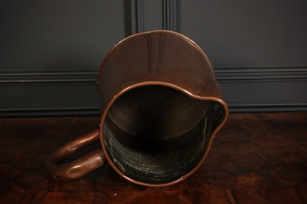 A large polished antique copper jug featuring a sturdy hollow handle, tapered body, and integrated pouring spout. View V