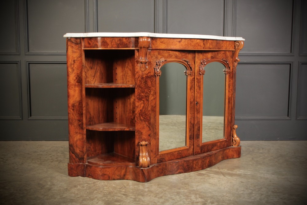 A Victorian burr walnut side cabinet featuring a white marble top, curved side shelves, and mirrored doors flanked by carved corbels.