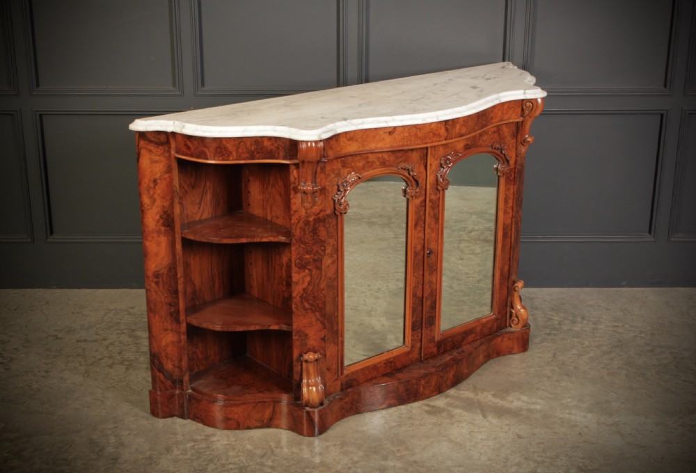 A Victorian burr walnut side cabinet featuring a white marble top, curved side shelves, and mirrored doors flanked by carved corbels. View II