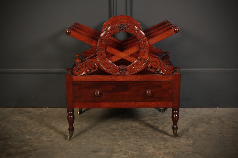 A William IV dark rosewood Canterbury magazine rack featuring four open compartments with carved decorative divisions above a single base drawer on turned legs with brass castors. View II