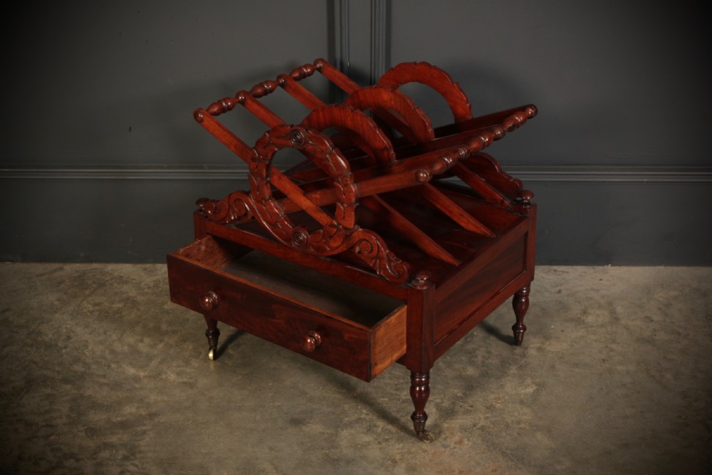 A William IV dark rosewood Canterbury magazine rack featuring four open compartments with carved decorative divisions above a single base drawer on turned legs with brass castors. View VIII